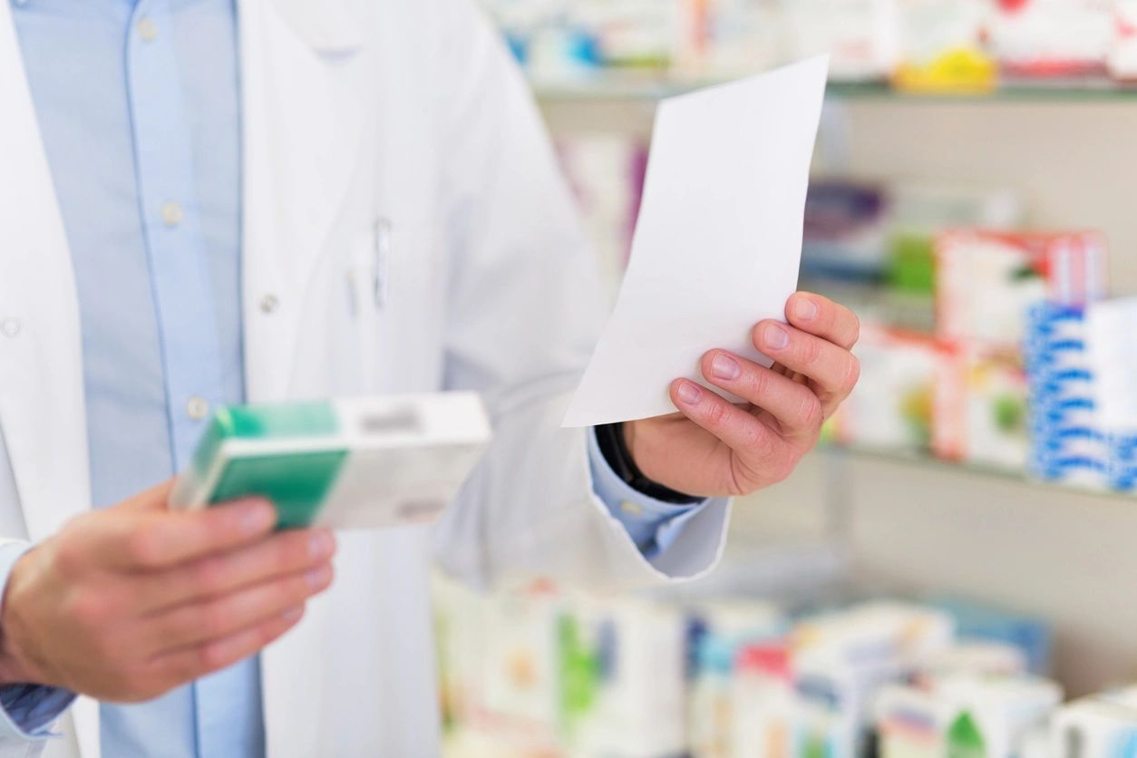 pharmacist holding a prescription in hand for medicare part d plans compared